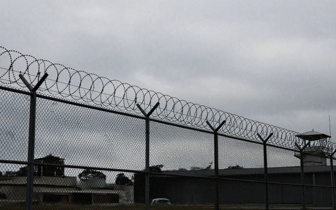 Immigration detention center exterior with fences and guard tower.