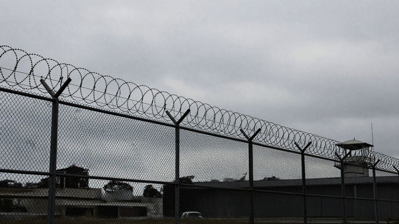 Immigration detention center exterior with fences and guard tower.